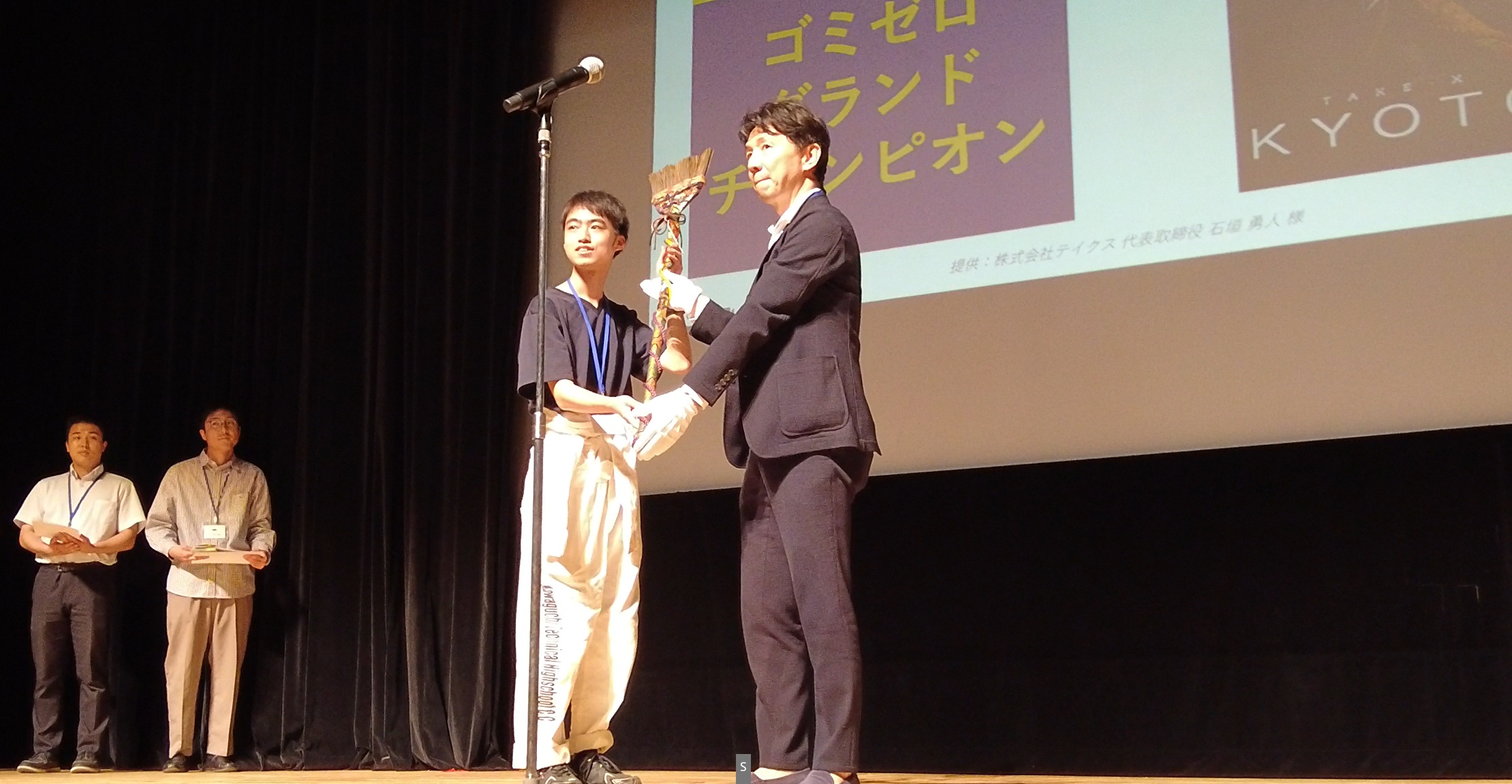 ゴミゼログランドチャンピオンの鈴木薫選手に西陣織「優勝ホウ旗」を授与する様子